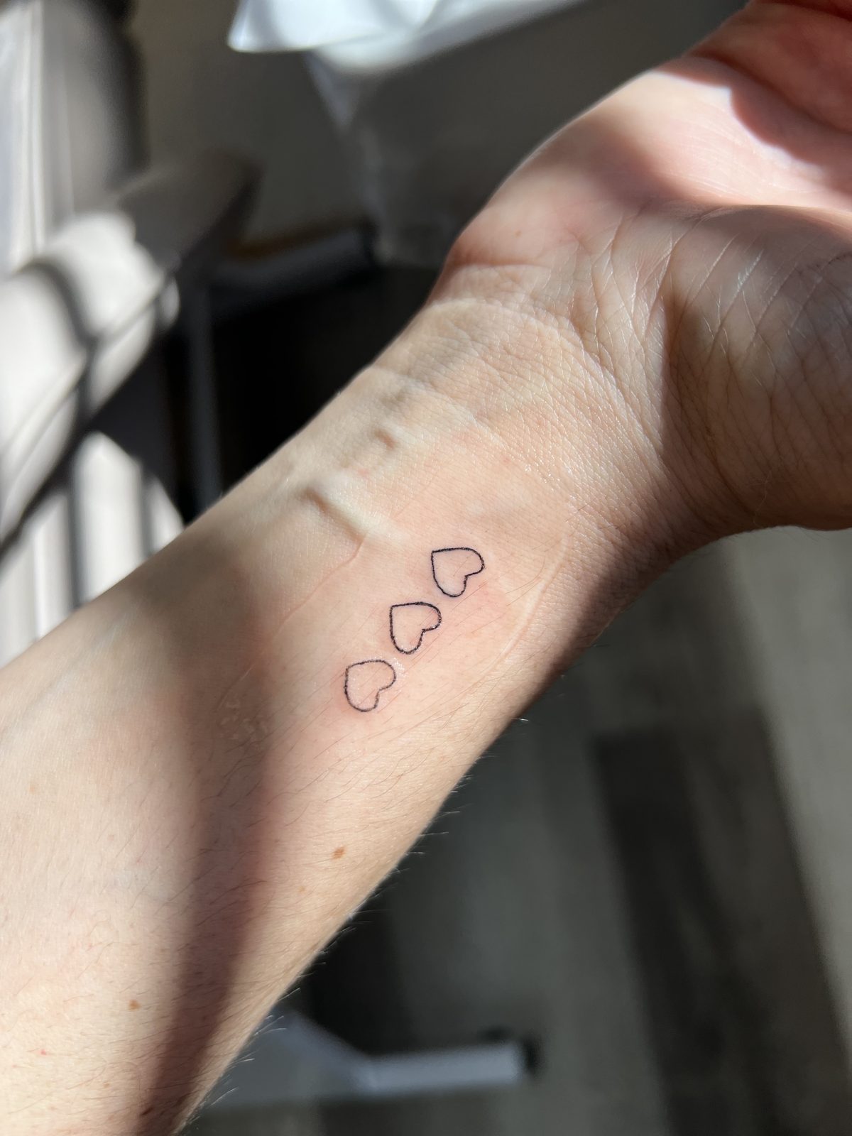 Mini tattoo — three small hearts on the wrist